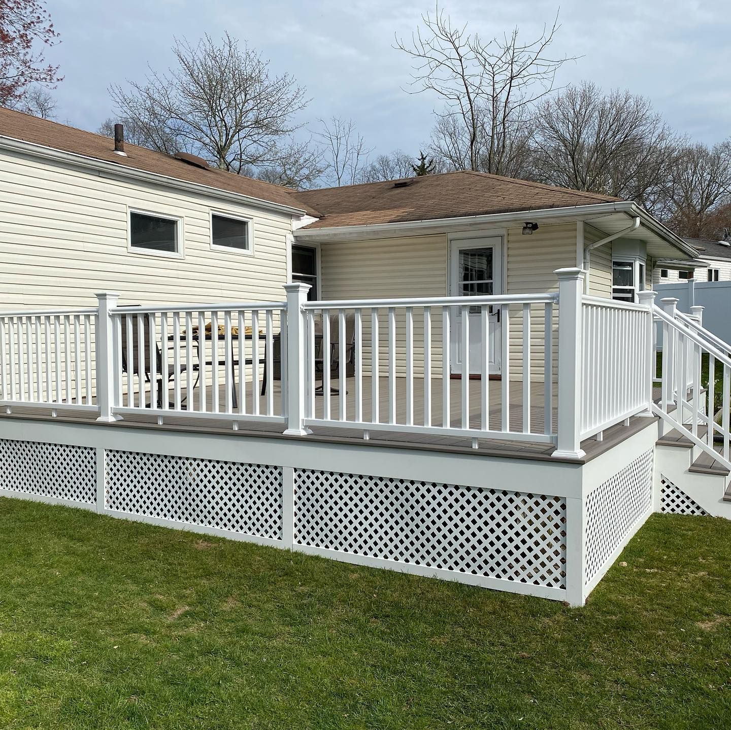 A white deck with stairs leading up to it in front of a house.