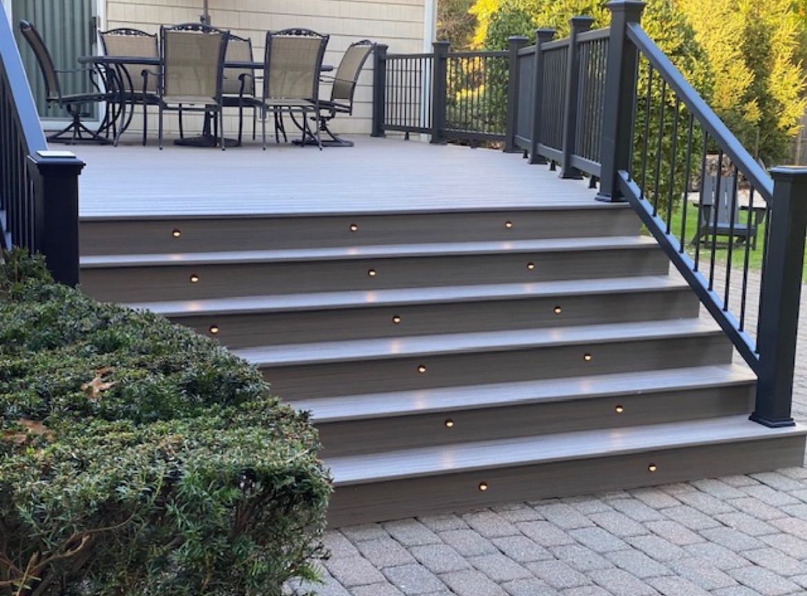 A deck with stairs leading up to it and a table and chairs on it.