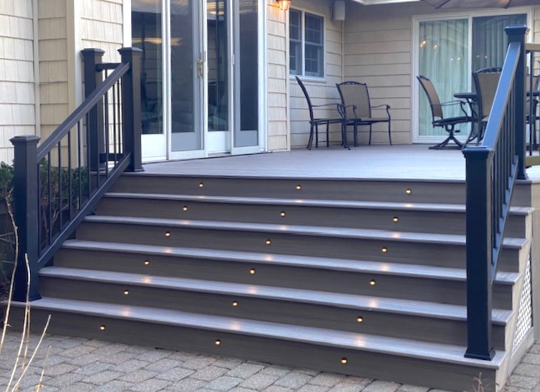 A deck with stairs leading up to it and a table and chairs on it.