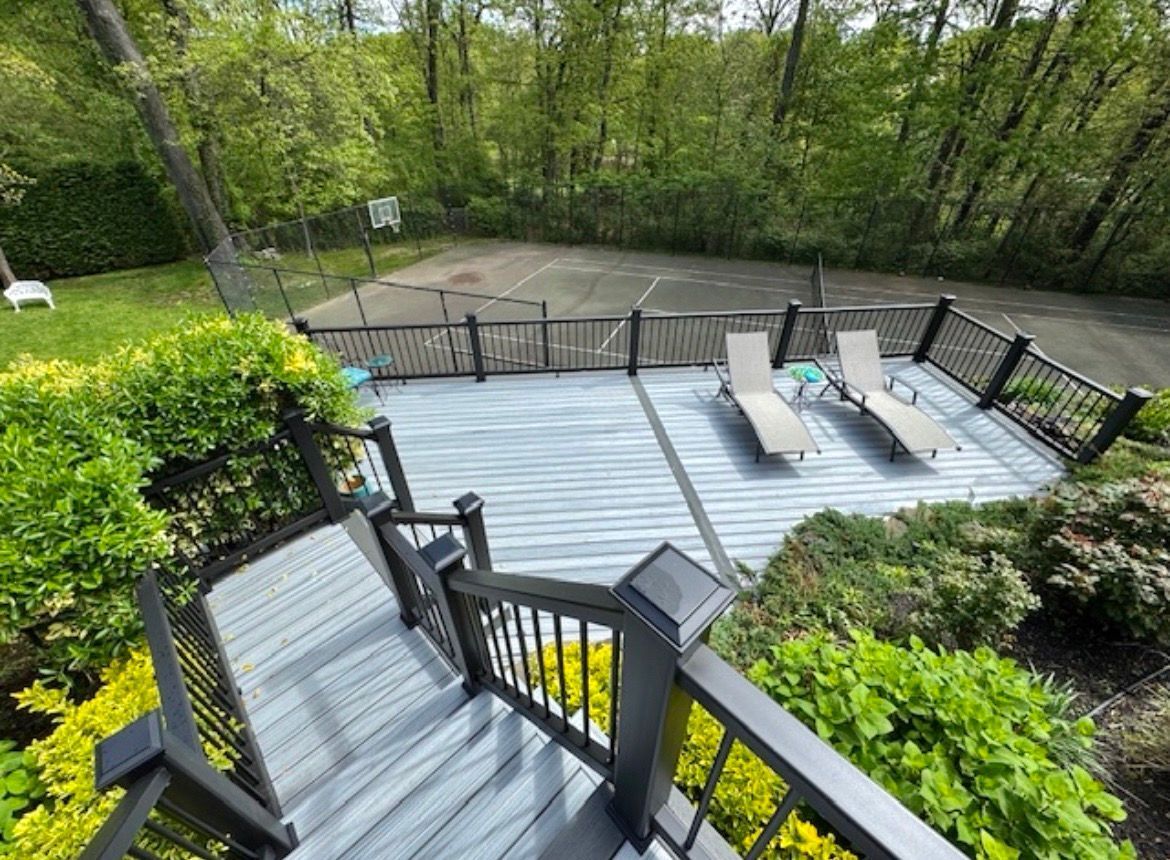 An aerial view of a deck with chairs and a tennis court in the background.