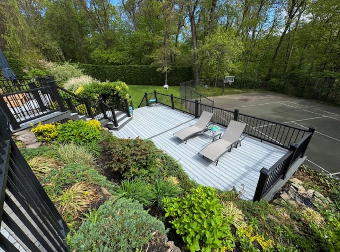 An aerial view of a deck with lounge chairs and a tennis court.