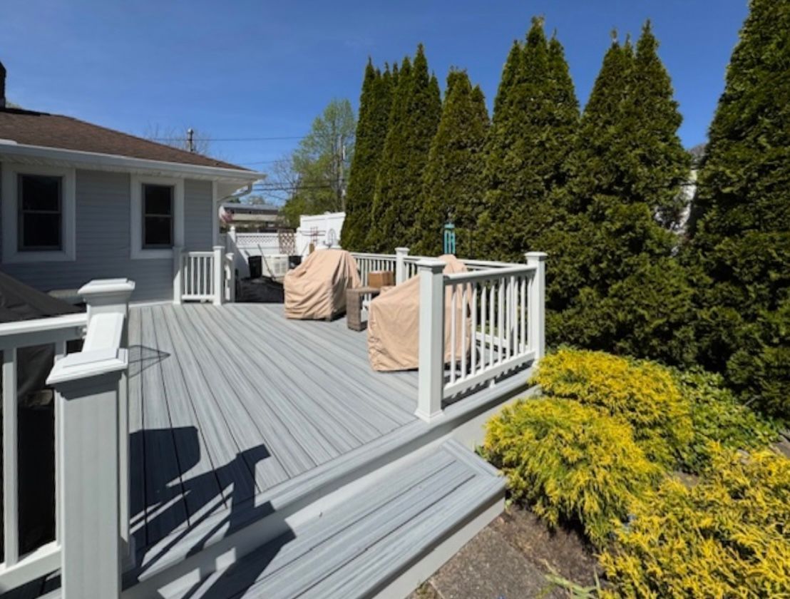 There is a large deck with a white railing and chairs on it.
