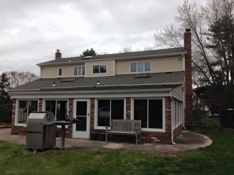 A large house with a grill and a bench in front of it.
