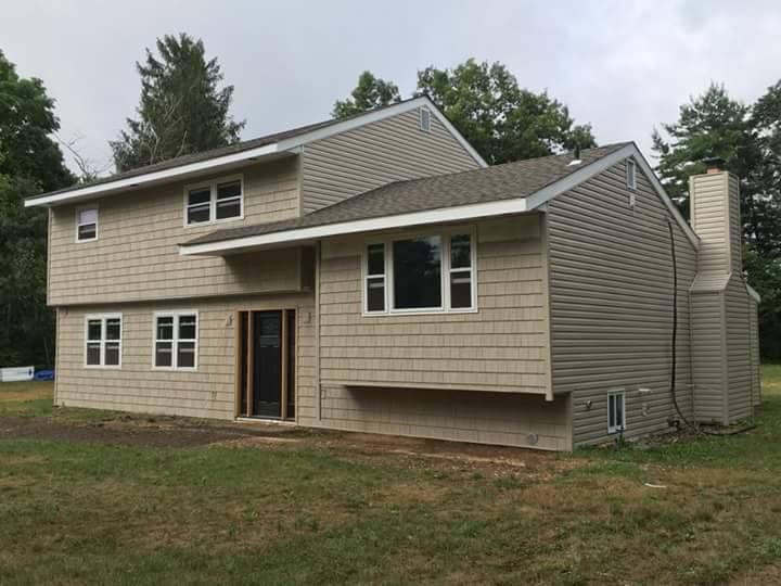 A large house with a lot of windows is sitting in the middle of a grassy field.