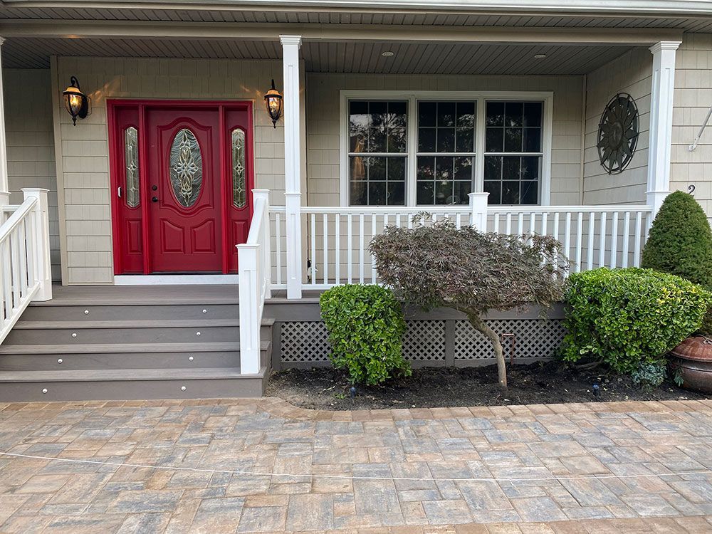 The front of a house with a red door and a white porch.