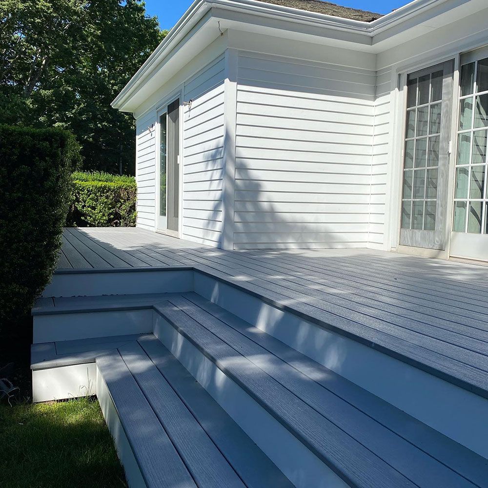 A white house with a deck and stairs leading up to it