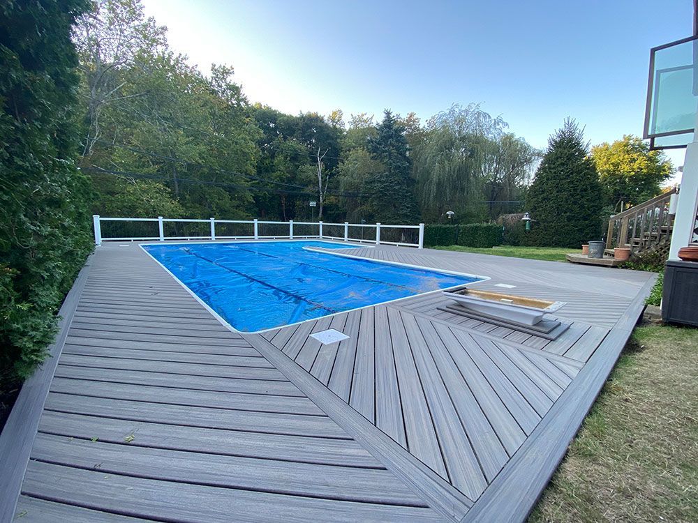 A large swimming pool is surrounded by a wooden deck.