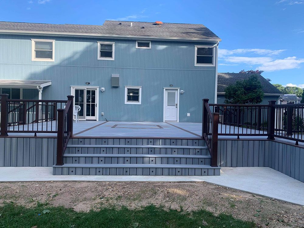 A blue house with a deck and stairs in front of it.