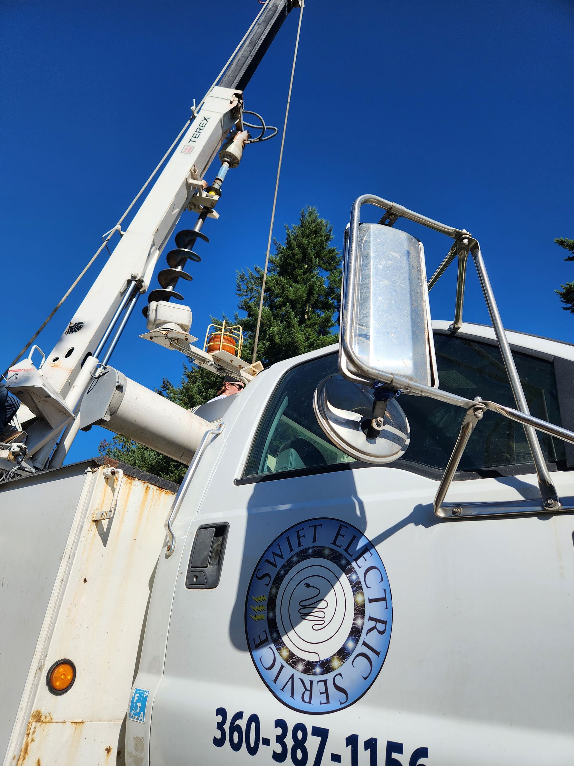 White utility truck with crane; blue sky, logo: