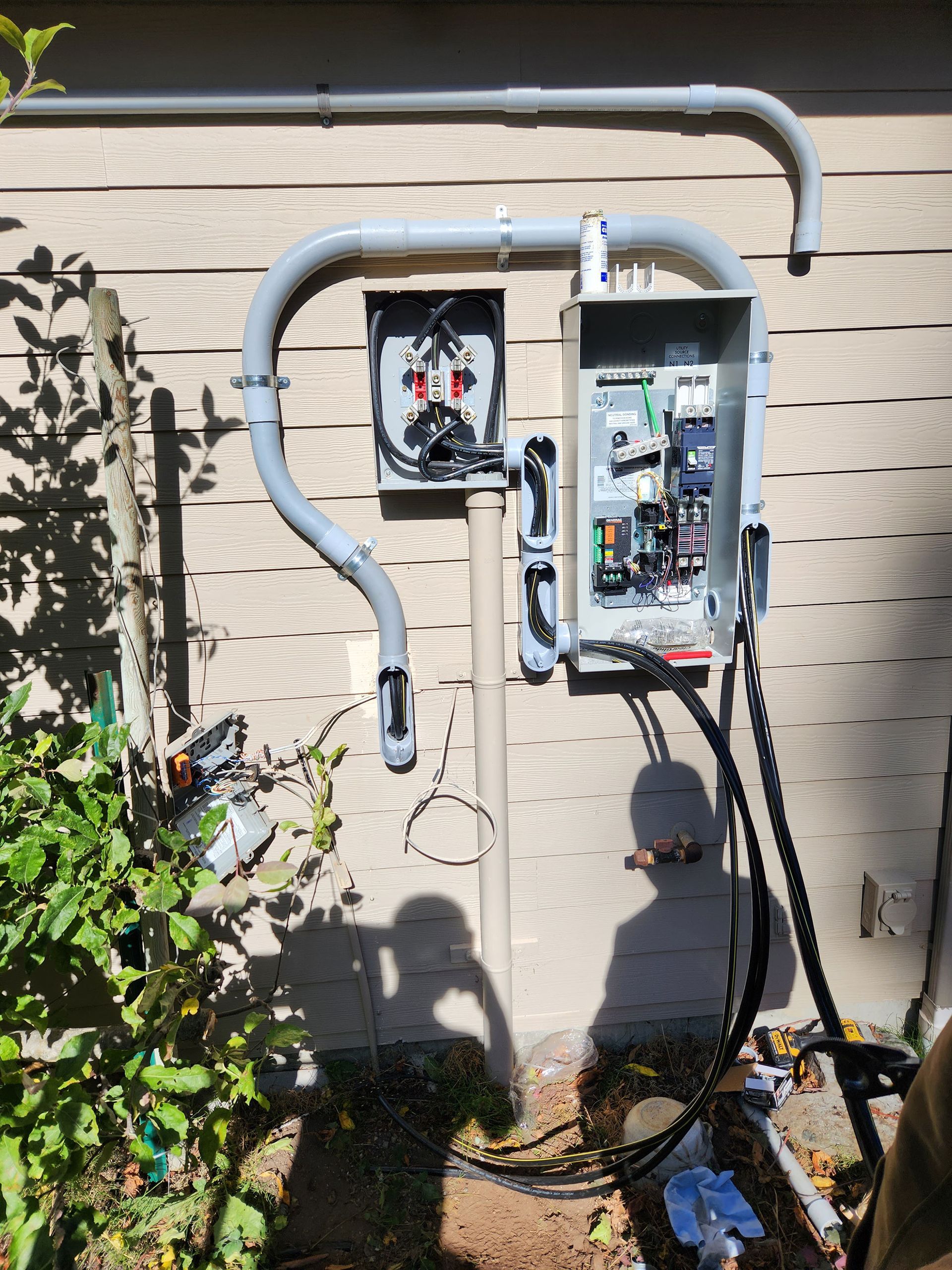 Electrical panel on exterior wall with conduit and wires.