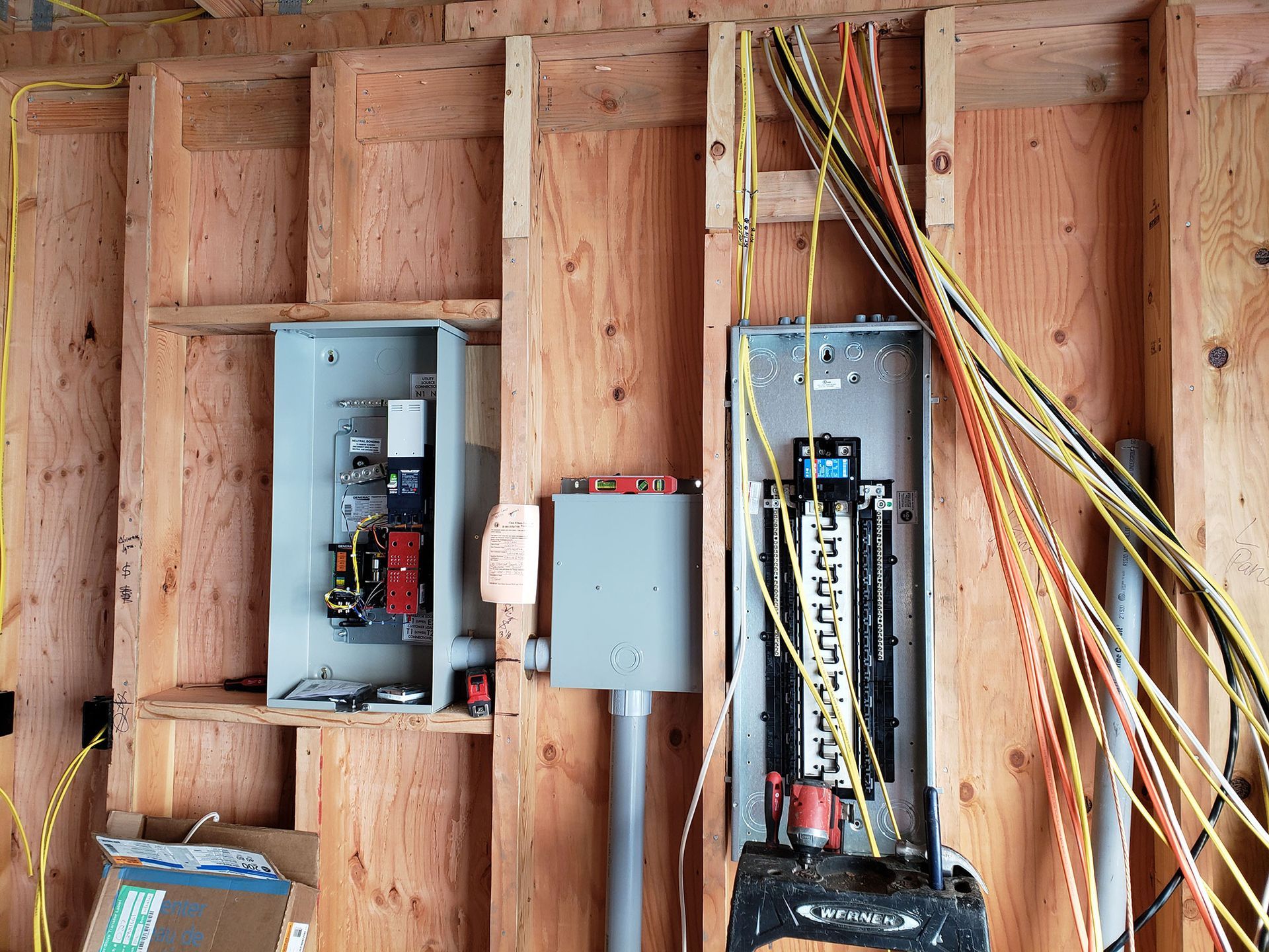 Electrical panels and wiring installed on a wooden wall during construction.