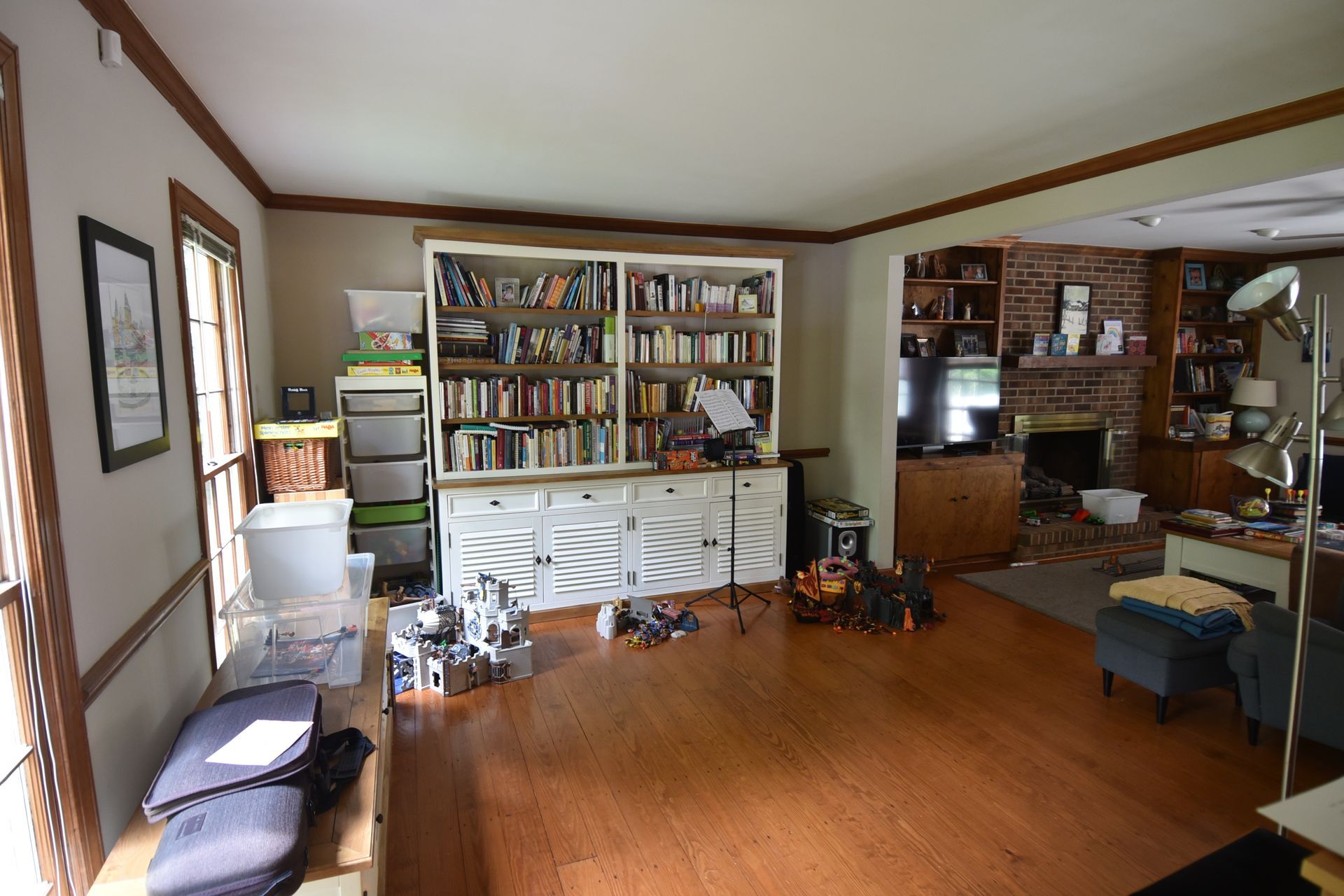 Living room with bookshelves, brick fireplace, and wooden floors.