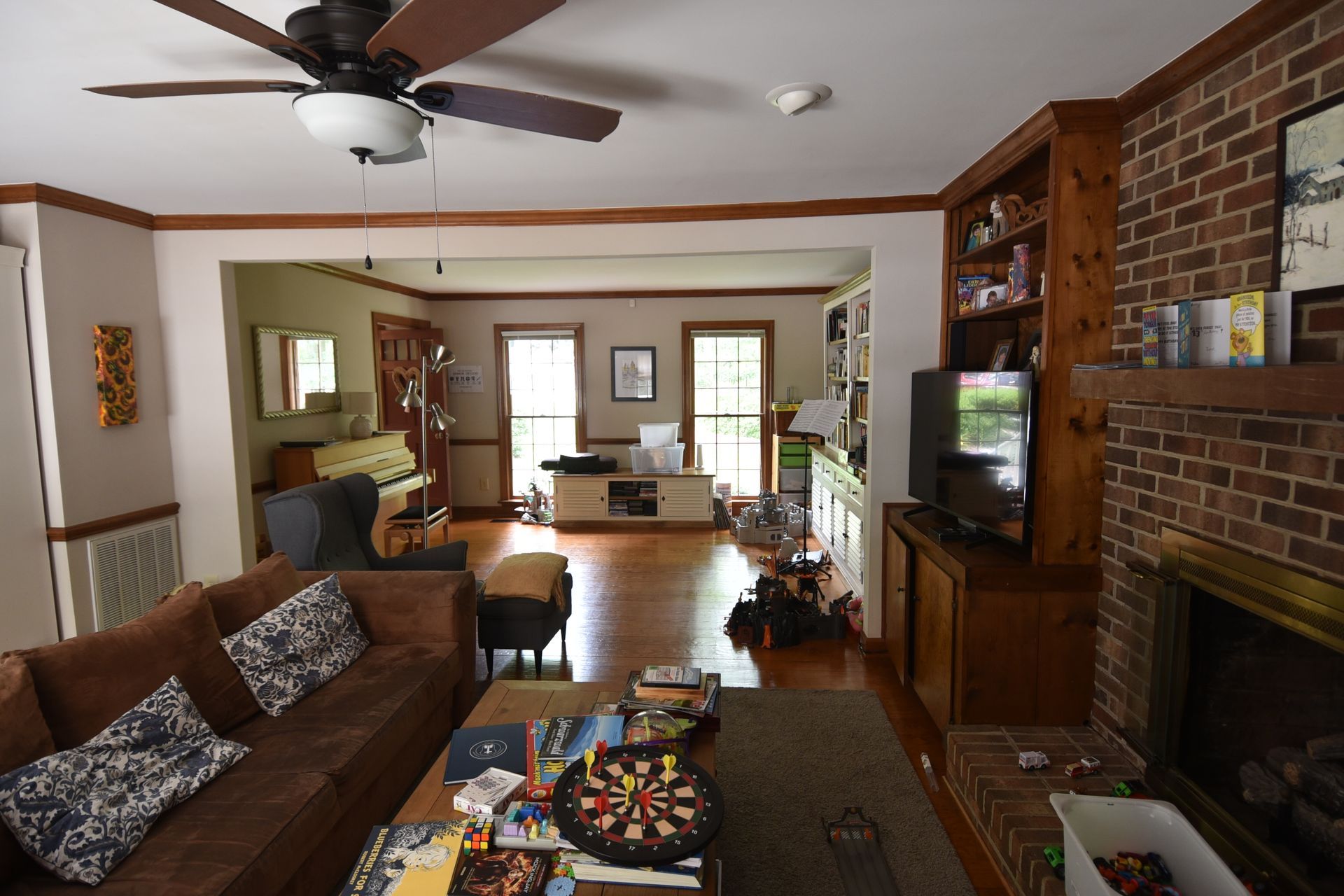 Cozy living room with a brown leather sofa, fireplace, and open doorway to another room.