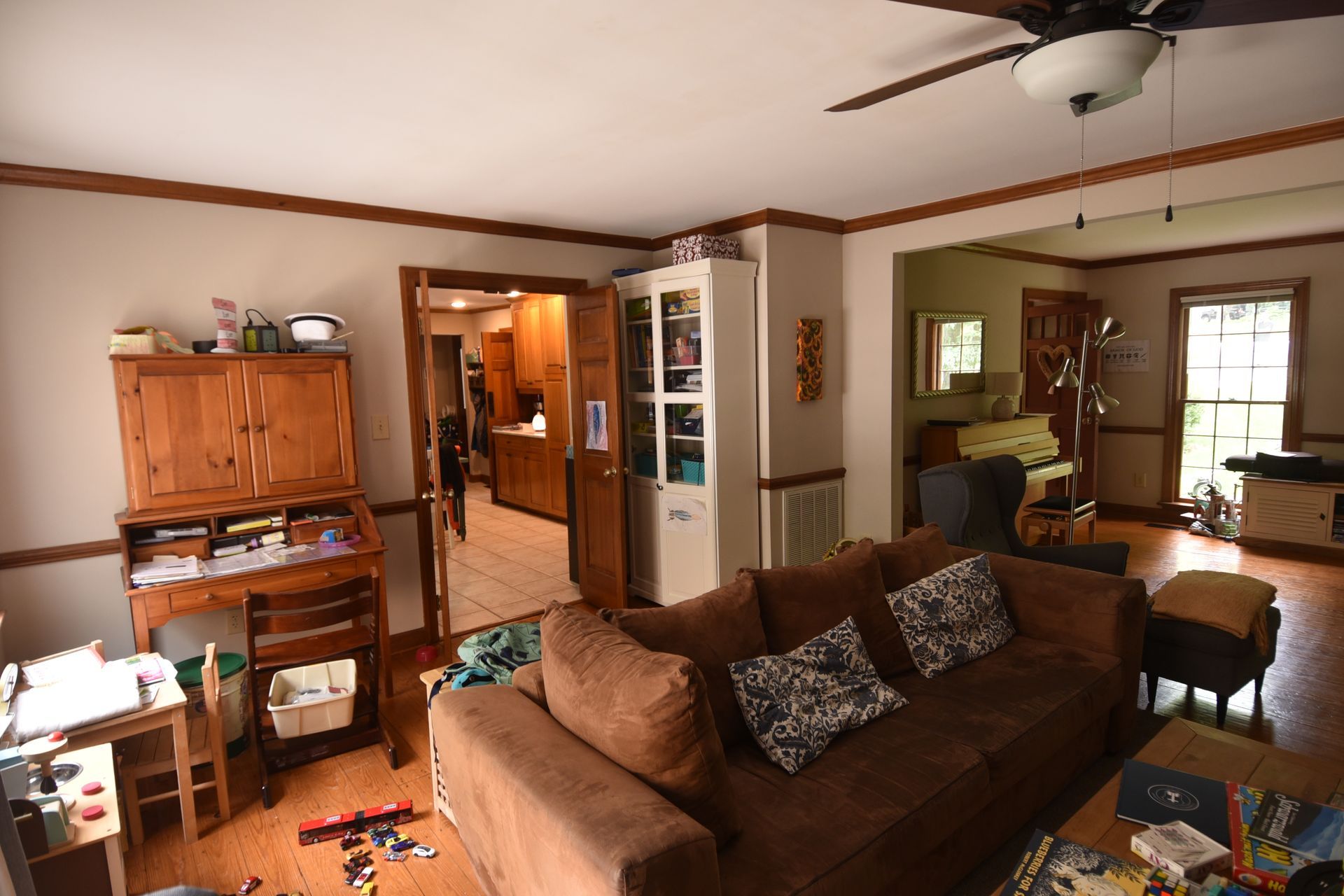 Living room with brown couch, desk, doorway to kitchen and exterior door.