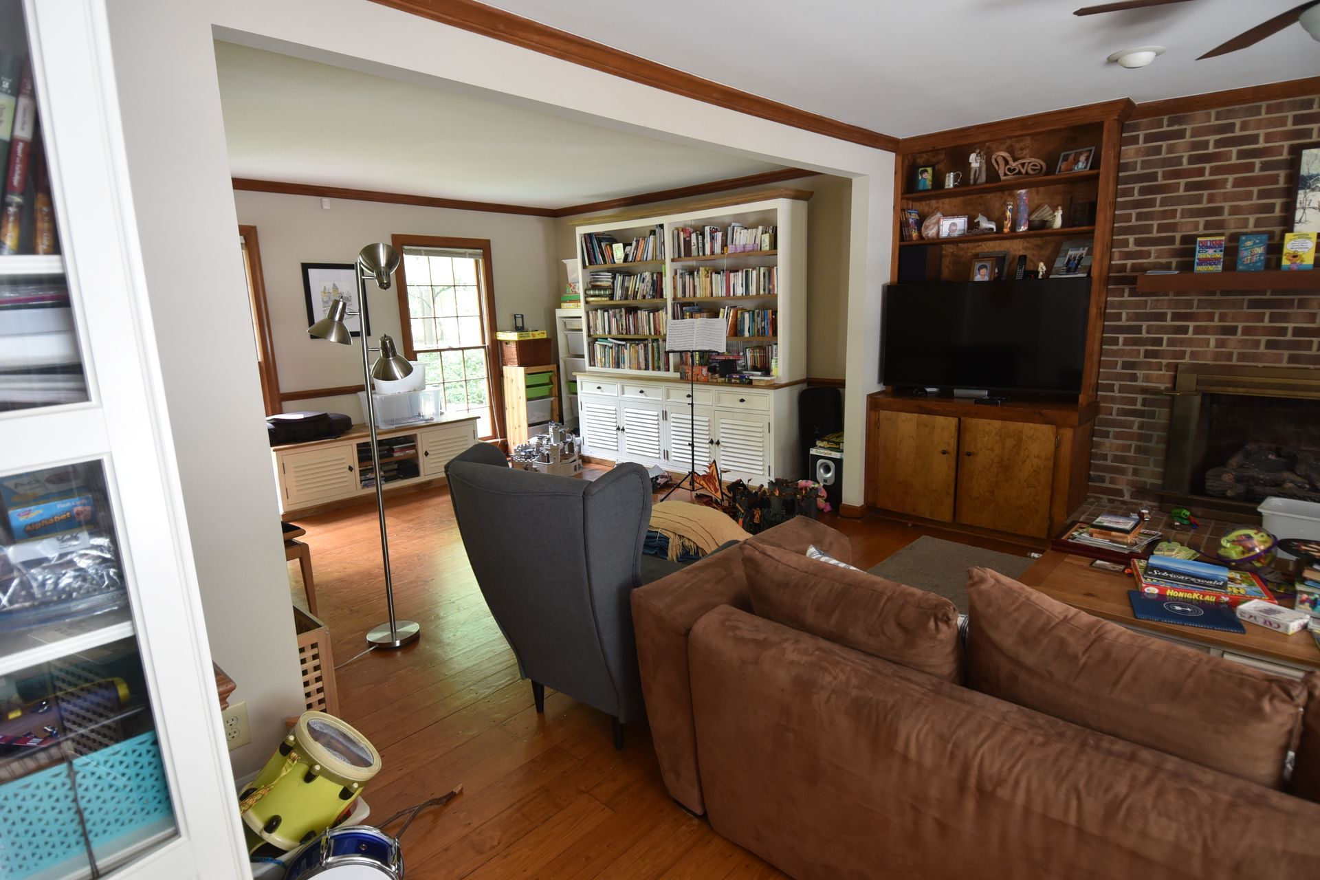 Cozy living room with a brick fireplace, bookshelves, and a brown couch.