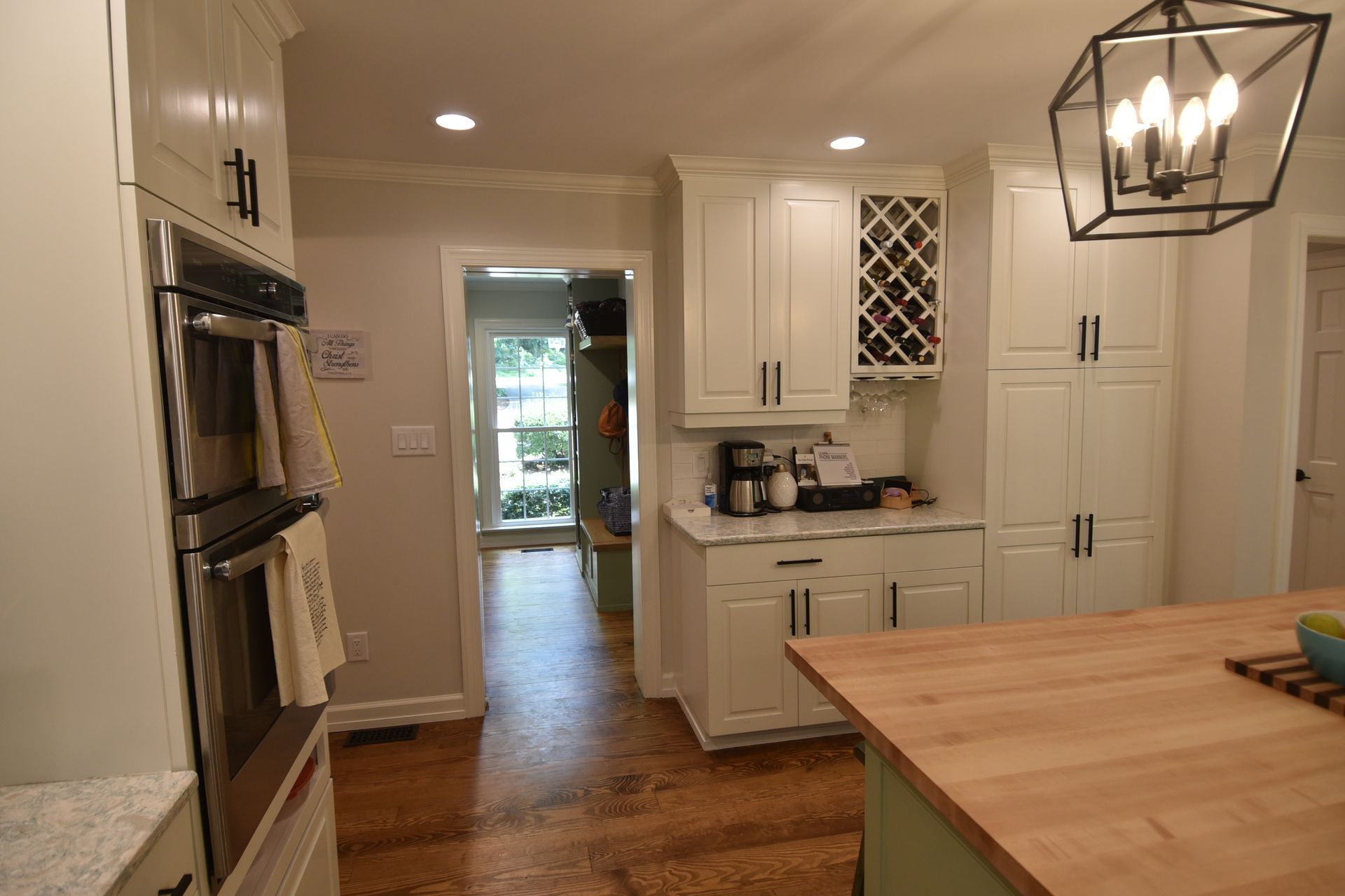 Kitchen with white cabinets, wood countertops, and a view into a hallway.