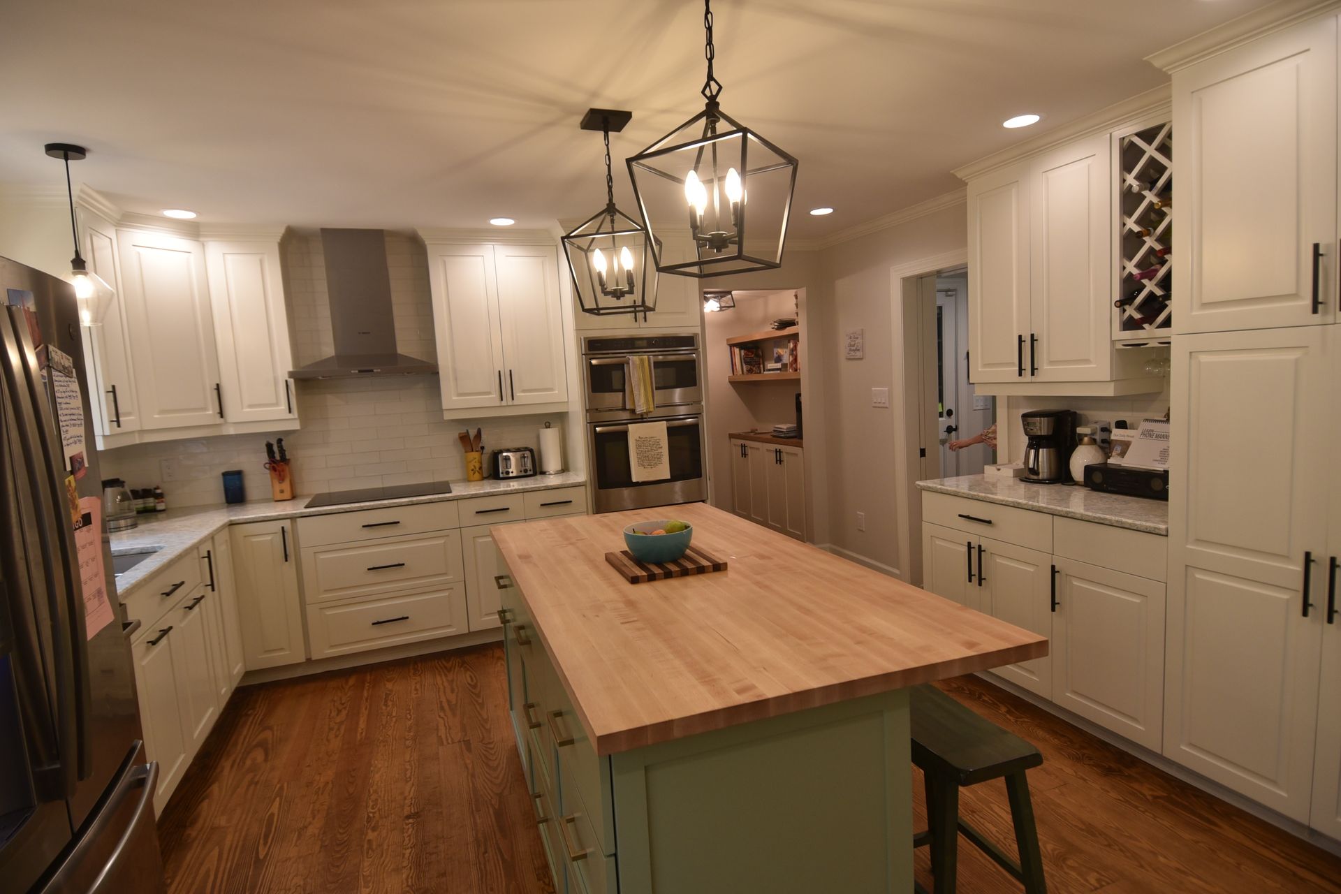 Kitchen with white cabinets, a wooden island, and pendant lights.