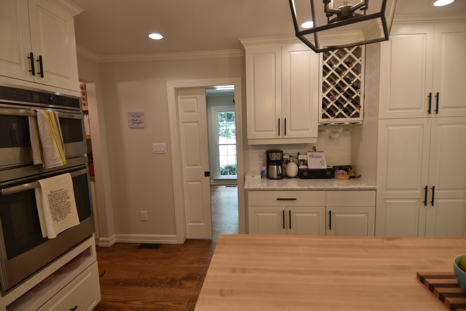 Bright kitchen with white cabinets, wood countertops, and a view into another room.