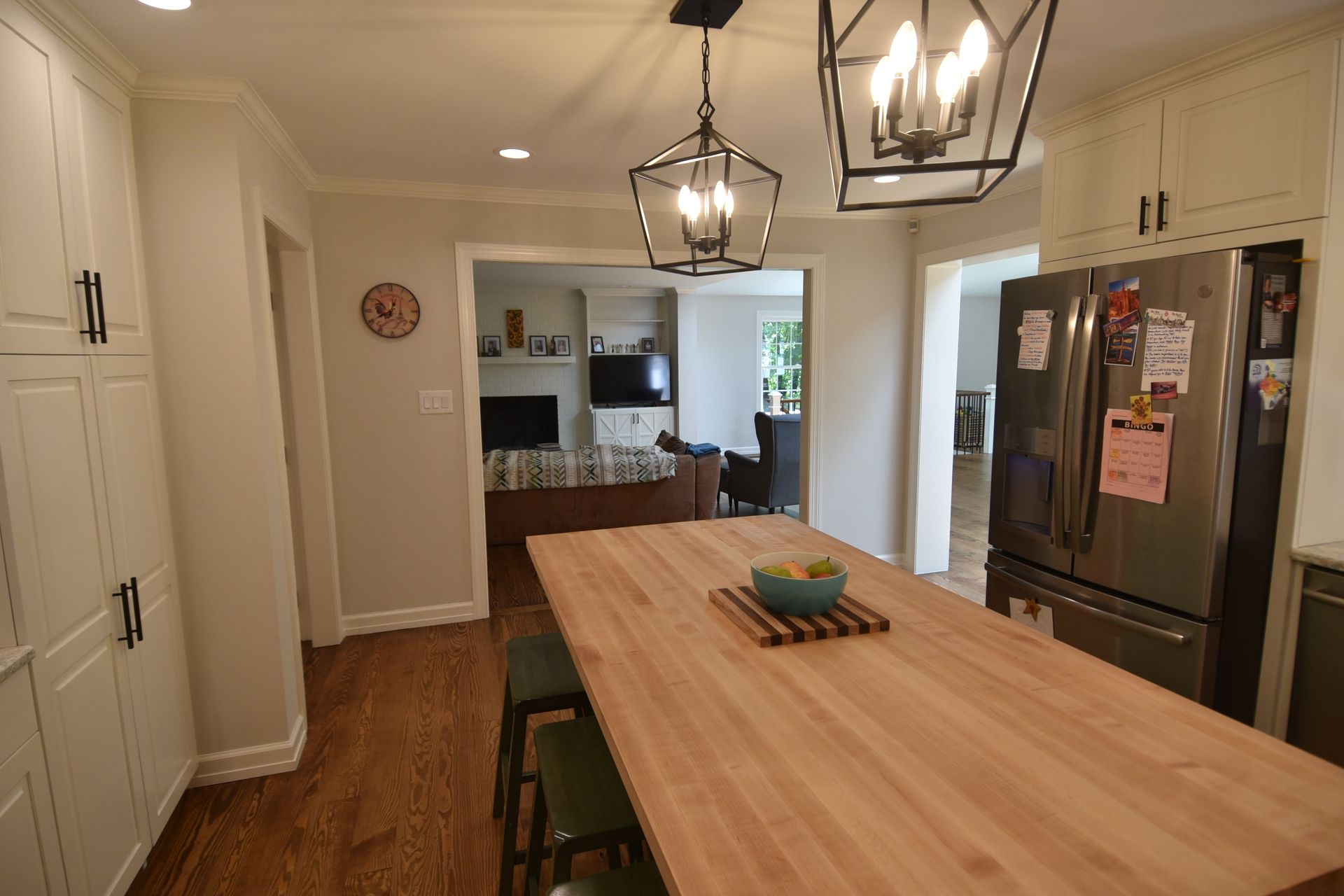 A kitchen with white cabinets, a wooden island, and a view into the living room.