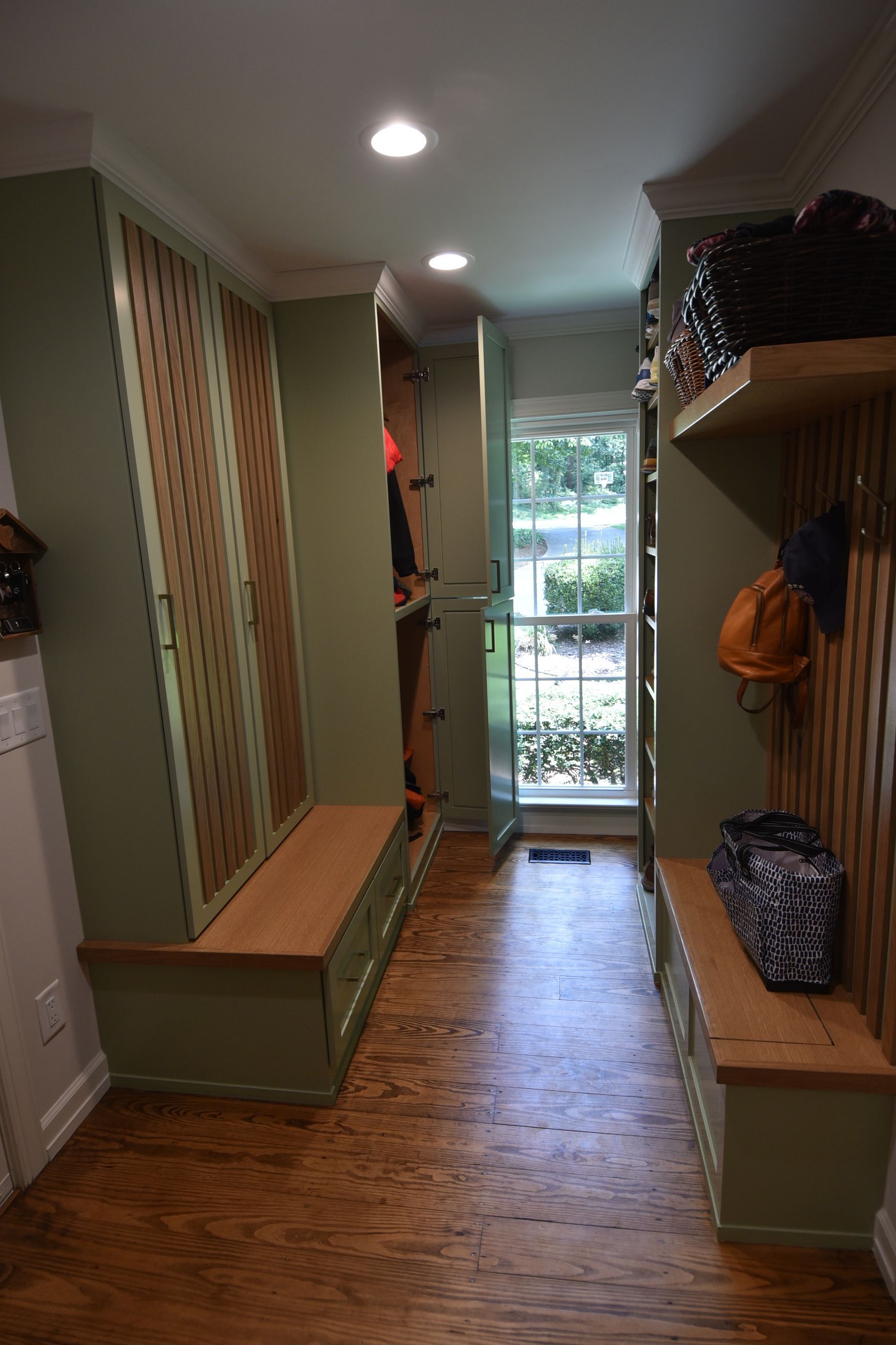 Hallway with green storage cabinets, wooden benches, and a window with outdoor view.