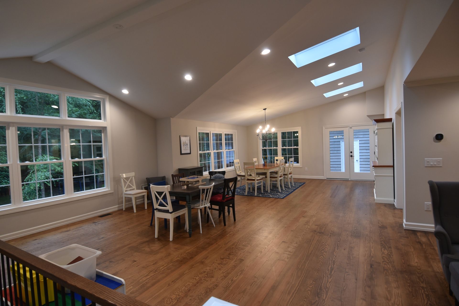 Spacious room with hardwood floors, skylights, and multiple tables for dining and playing games.