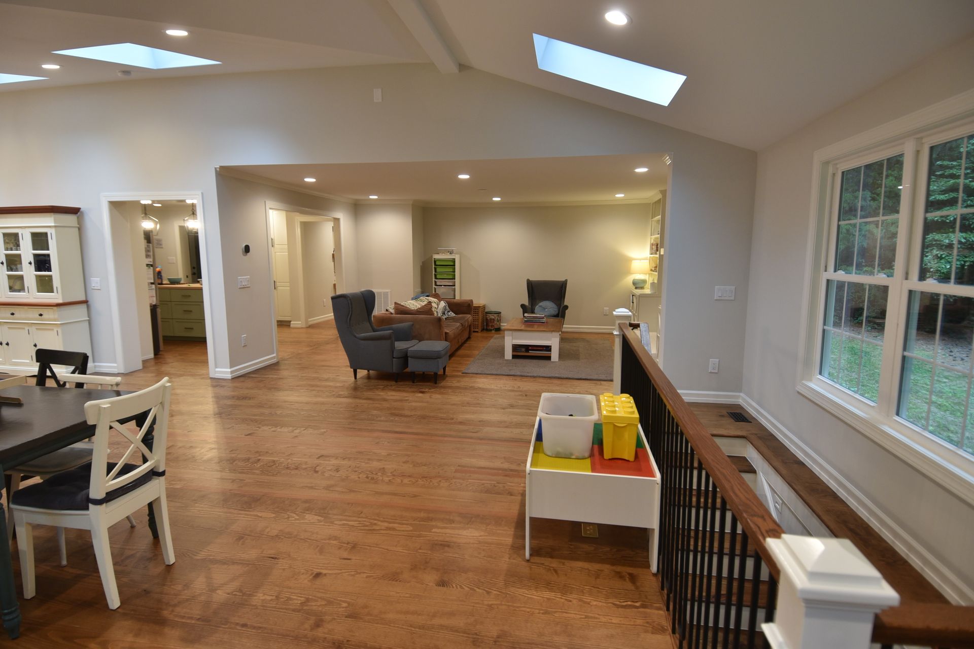 Spacious, light-filled living area with hardwood floors, a living room, dining area, and large windows.