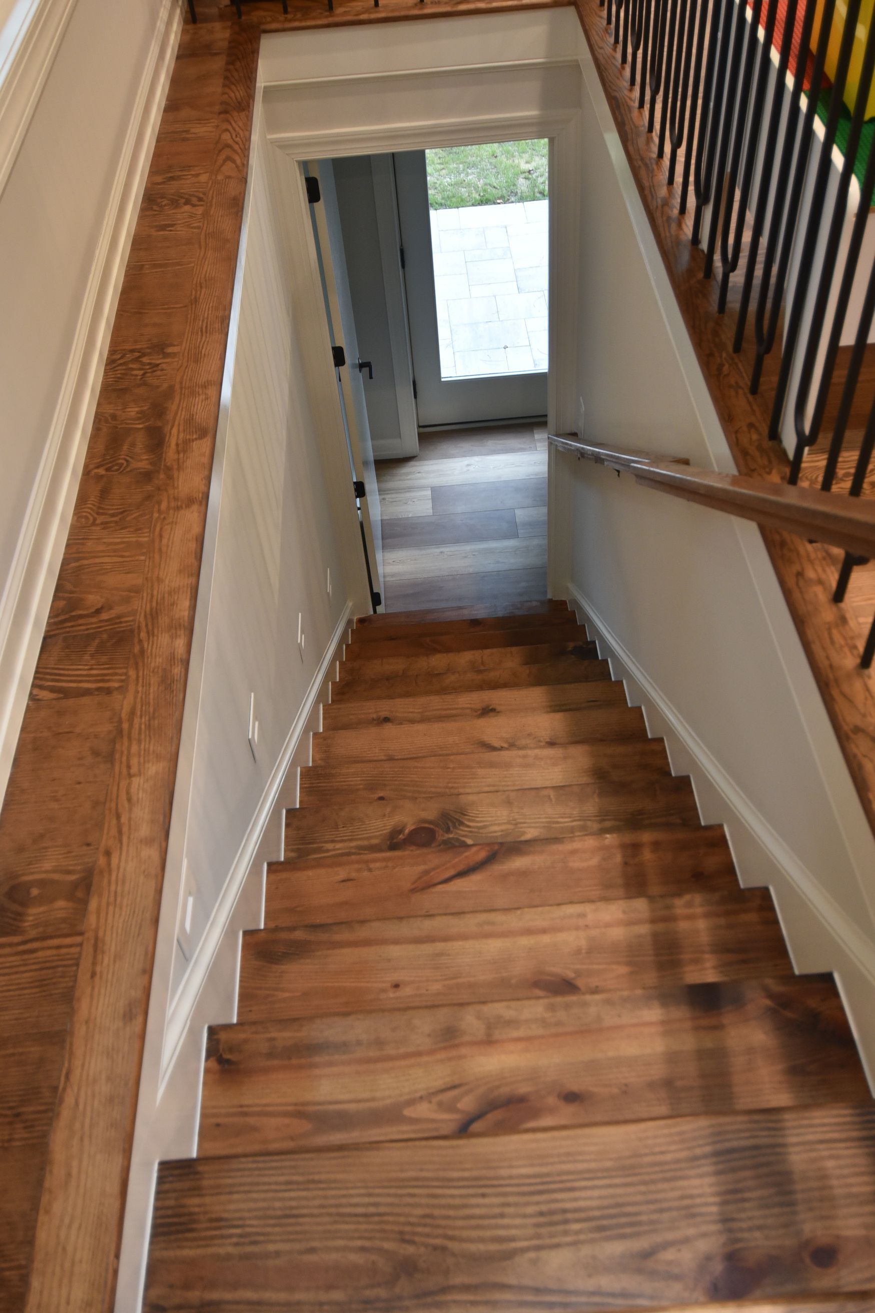Staircase with wooden steps and a wooden railing, leading downwards. Light shines at the bottom.