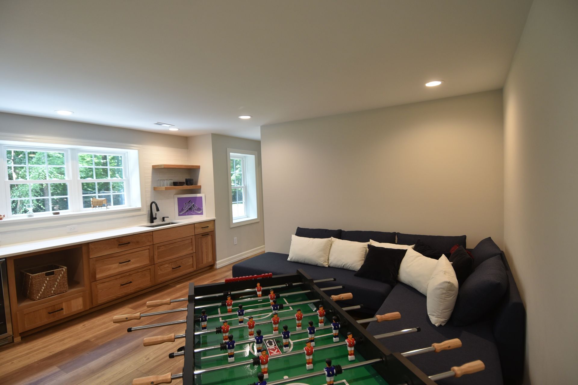 Game room with foosball table, blue sectional sofa, and wooden cabinetry.