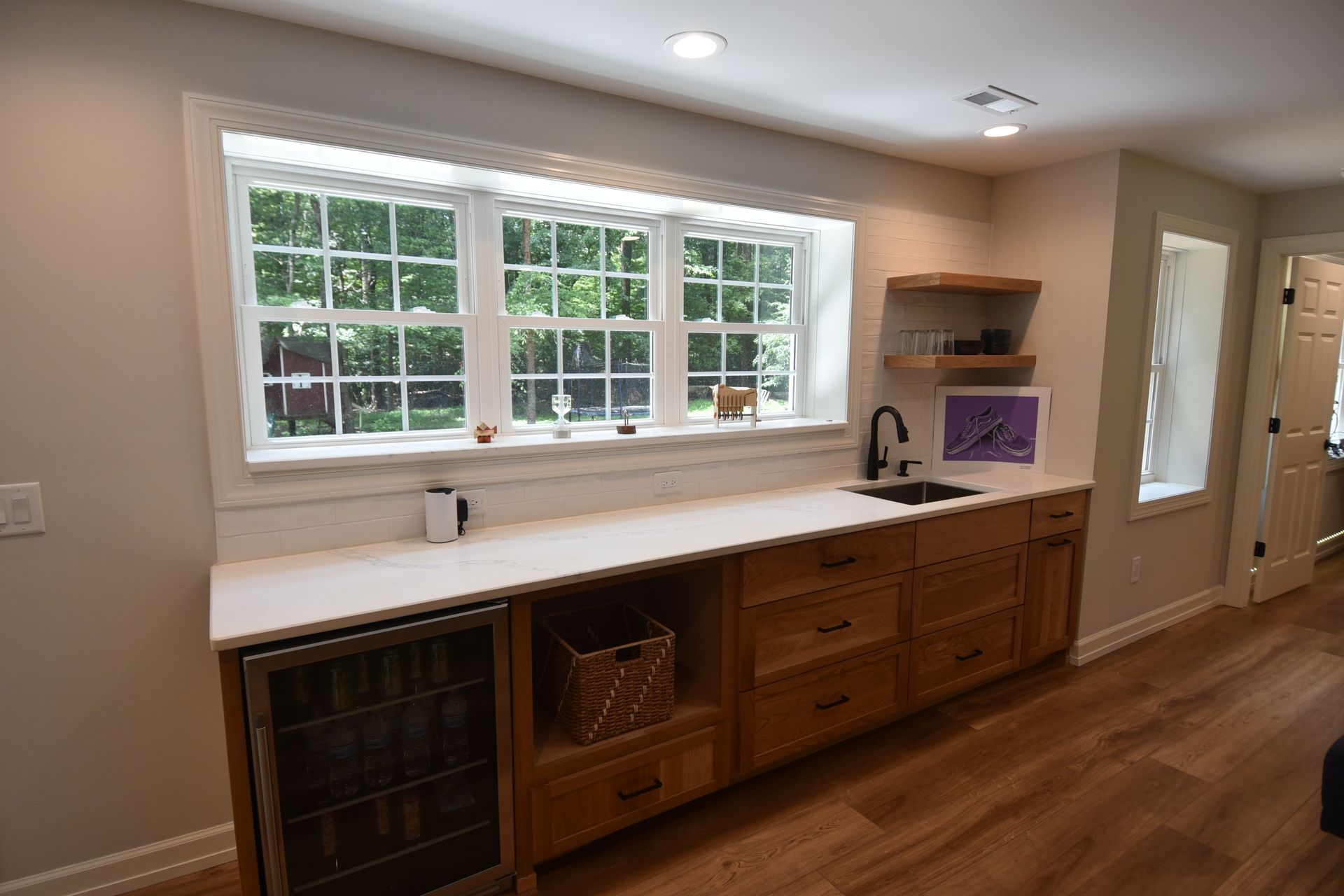 Bar area with window, sink, cabinets, and wine fridge.