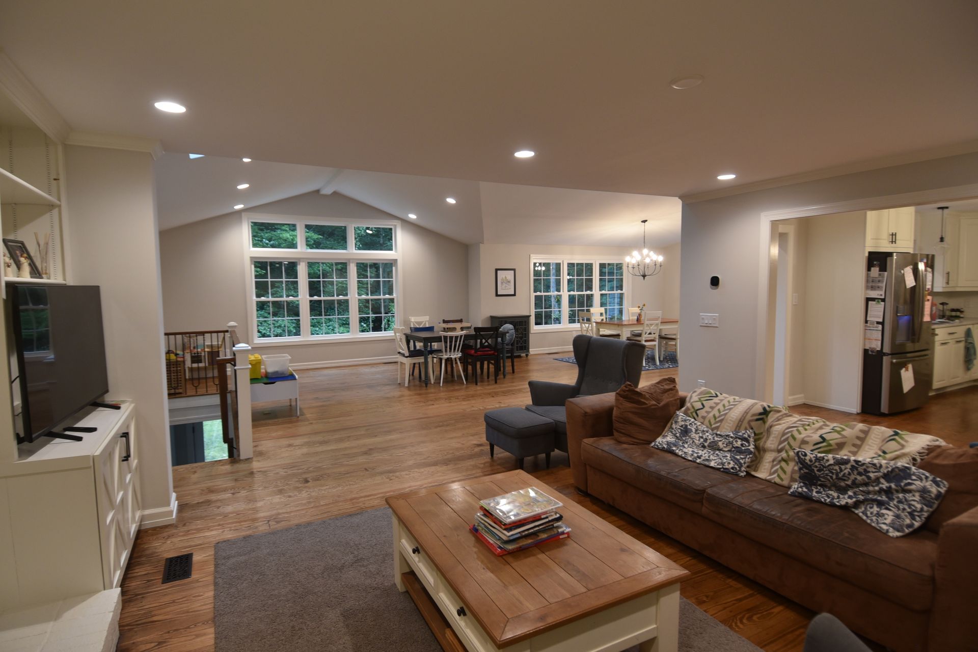 Open-concept living space with a brown leather couch, dining area, and kitchen visible.