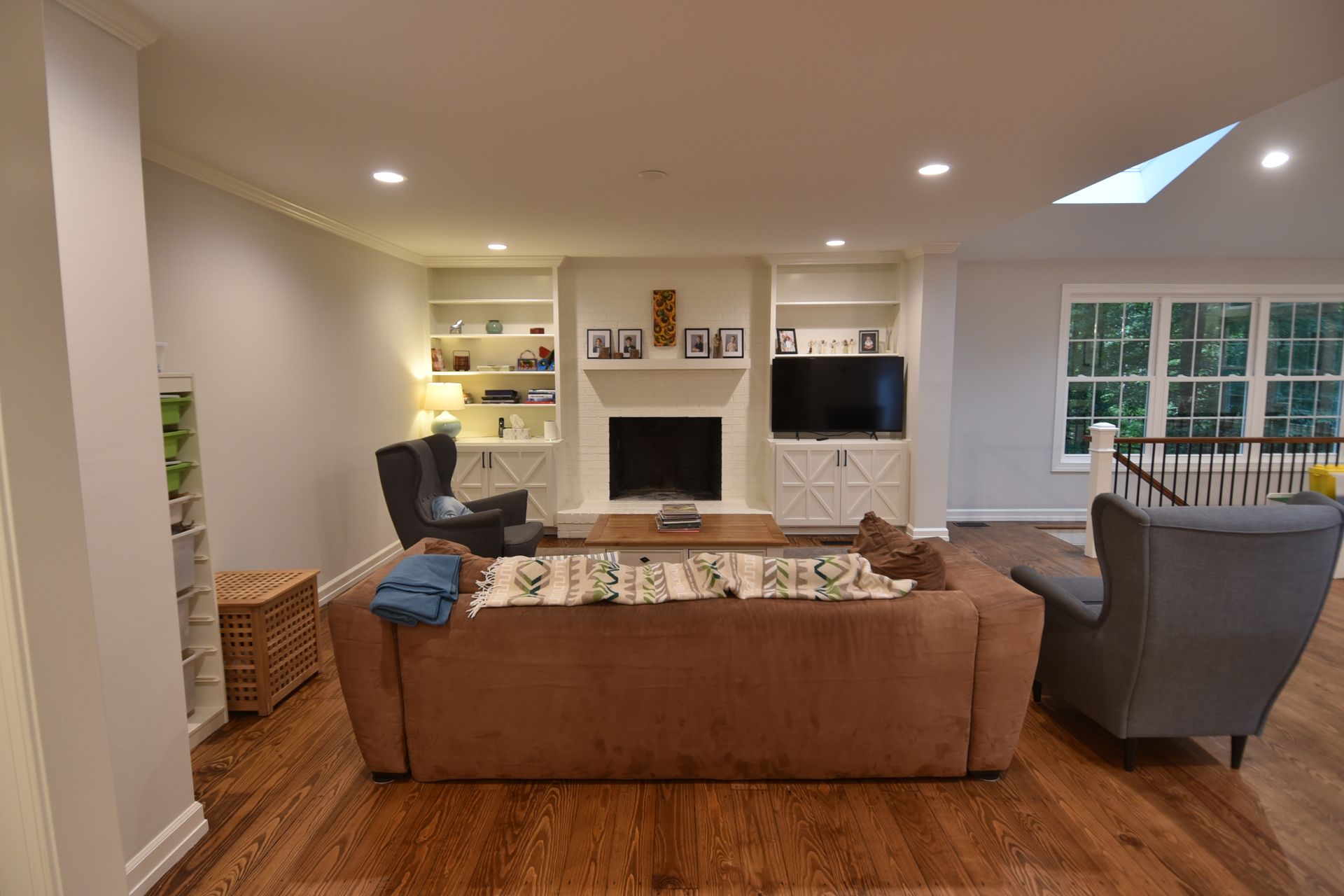 Living room with fireplace, built-in shelves, sofa, and two armchairs on hardwood floor.