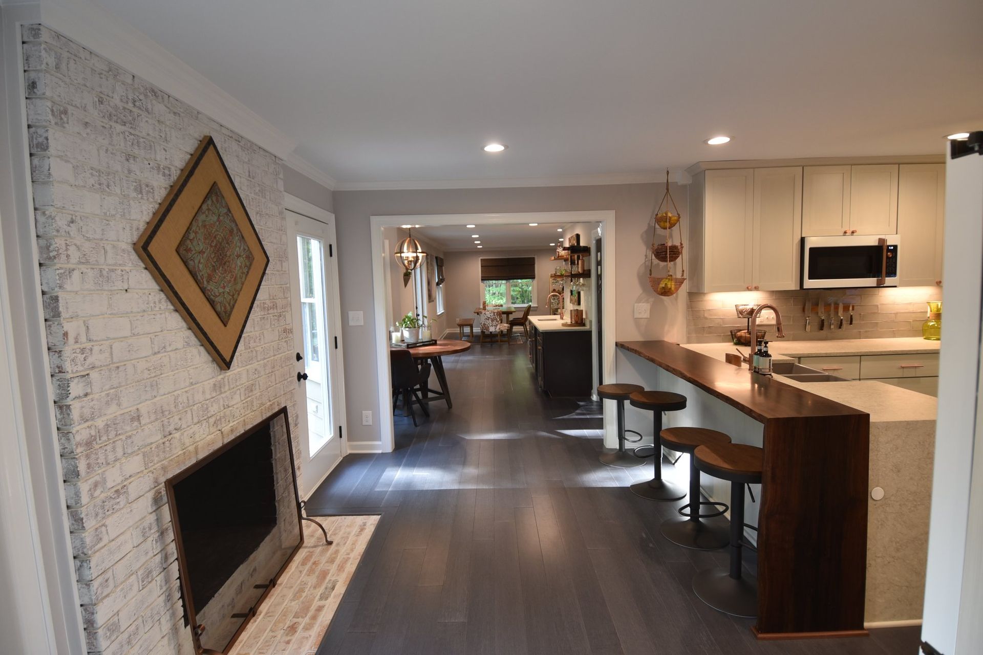 A living room with a fireplace and a kitchen in the background