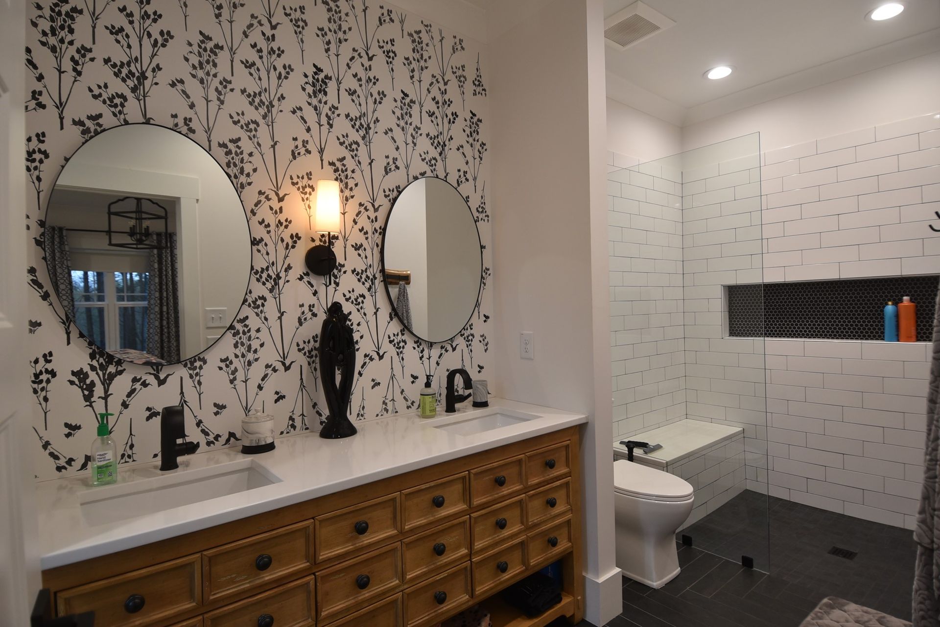 A bathroom with two sinks , two mirrors , a toilet , and a walk in shower.