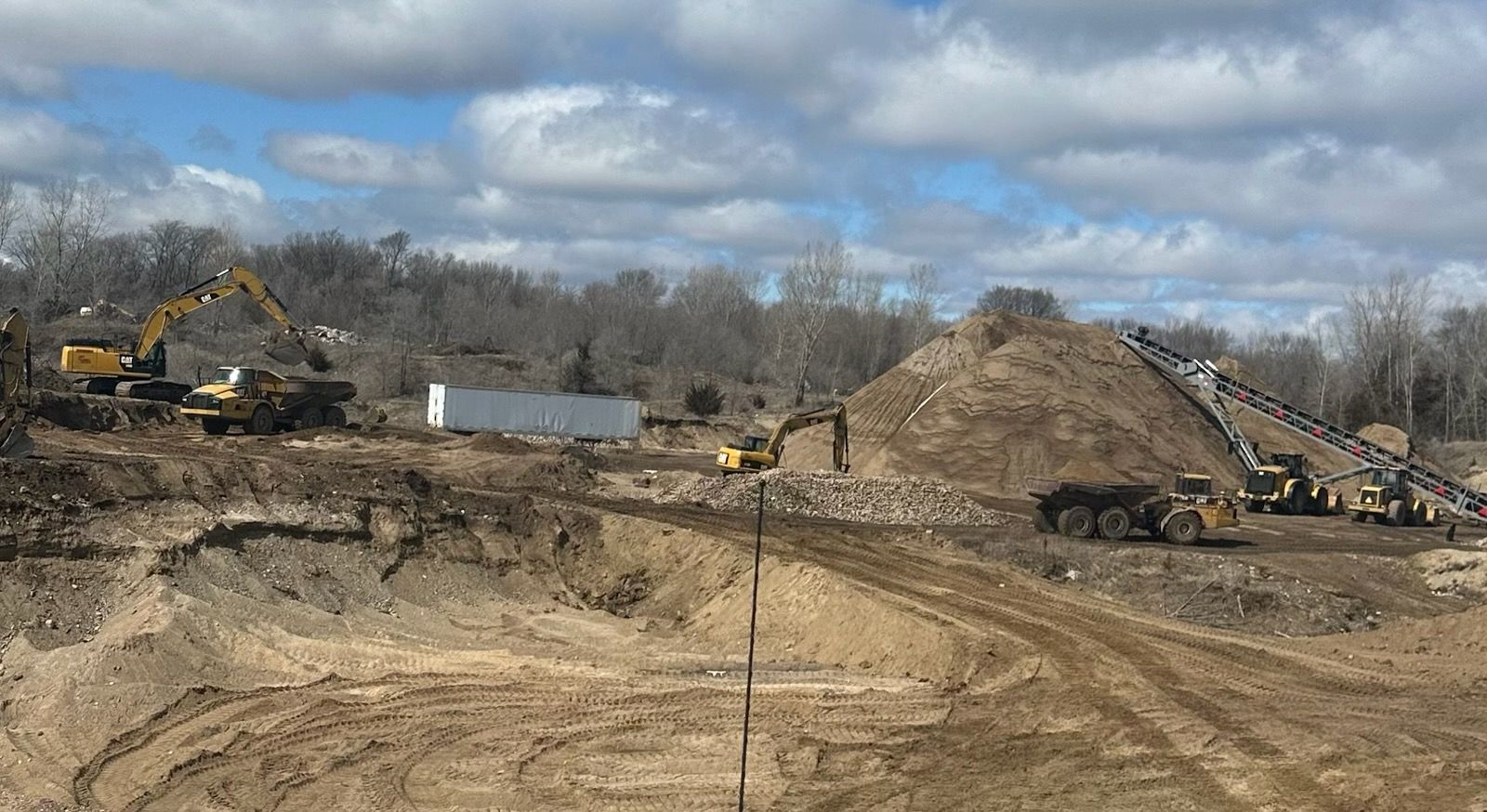 A large pile of sand is sitting on top of a field.