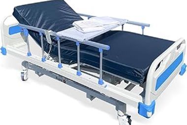 A white and blue medical hospital bed with an elevated head section and a tray table holding a folded white cloth.