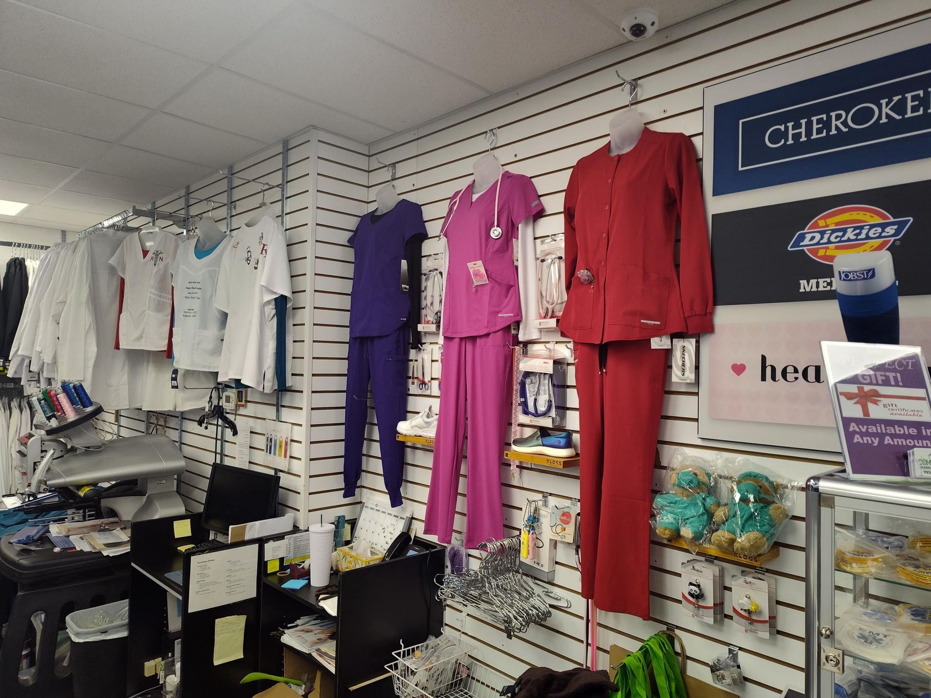 Store interior with scrubs displayed on mannequins and hanging on racks. Various colors and brands.