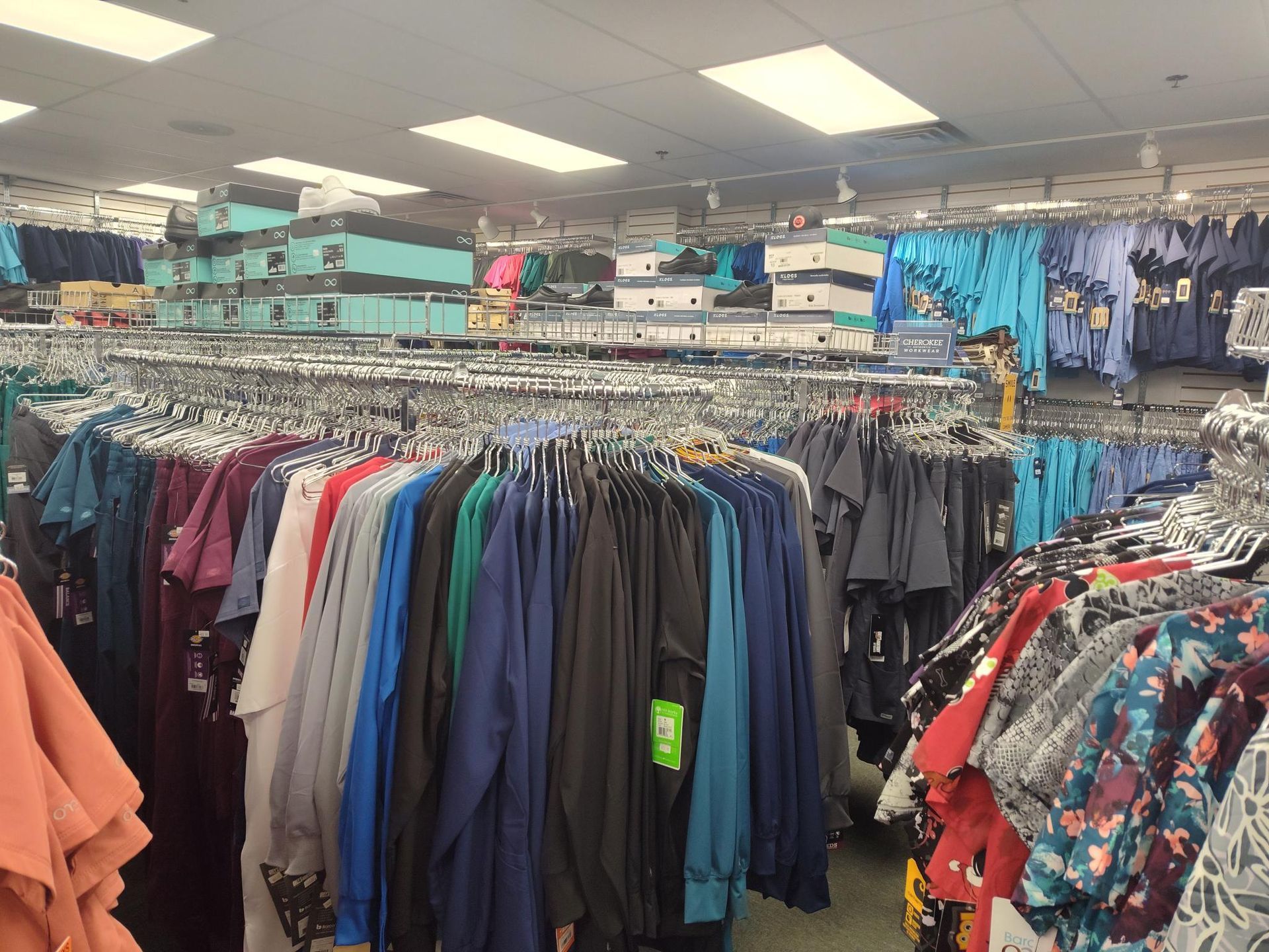 Clothing store interior with rows of hanging garments in various colors.