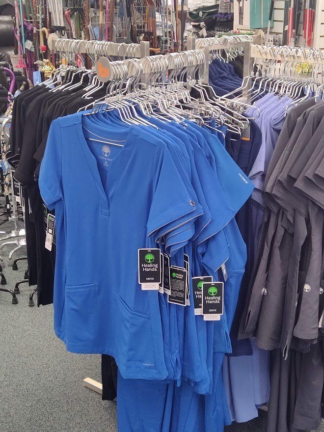 Blue scrubs hanging on racks in a retail store, with other scrub colors visible.