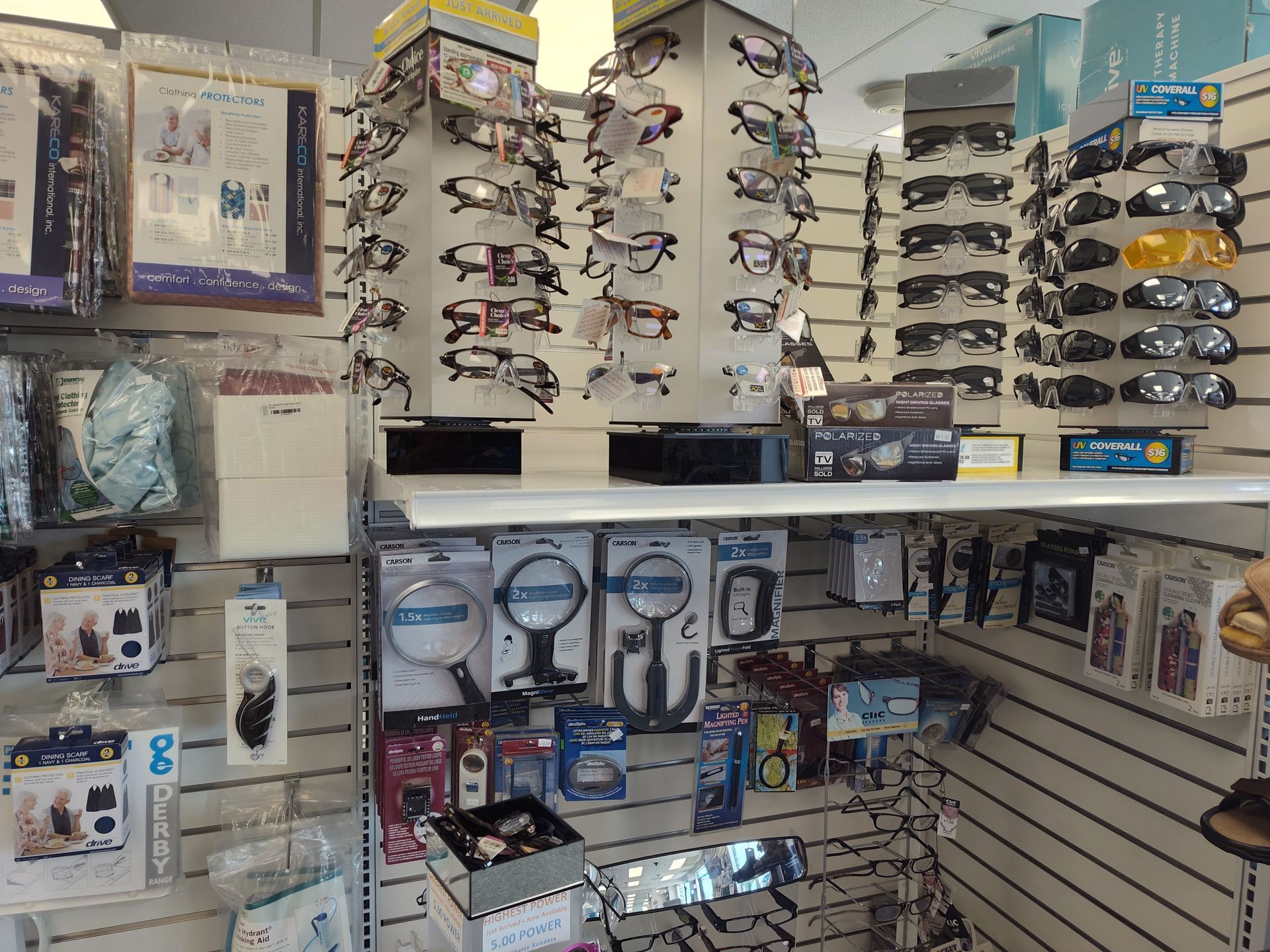 Eyeglass and magnifying glass display in a store, organized on shelves with various products.