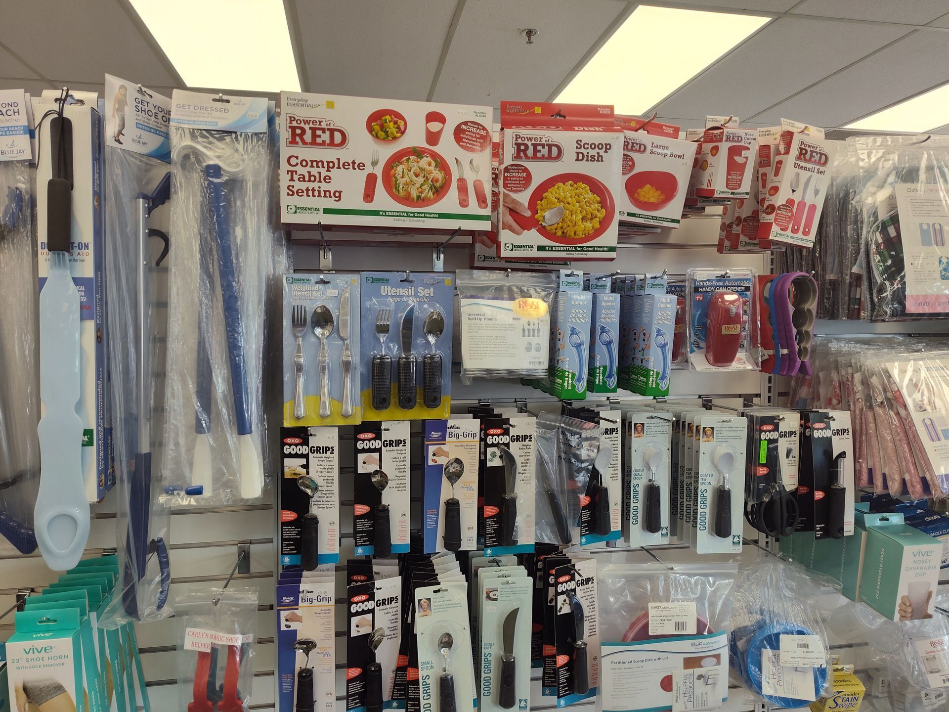 Wall display of packaged assistive eating utensils and kitchen tools in a retail setting.