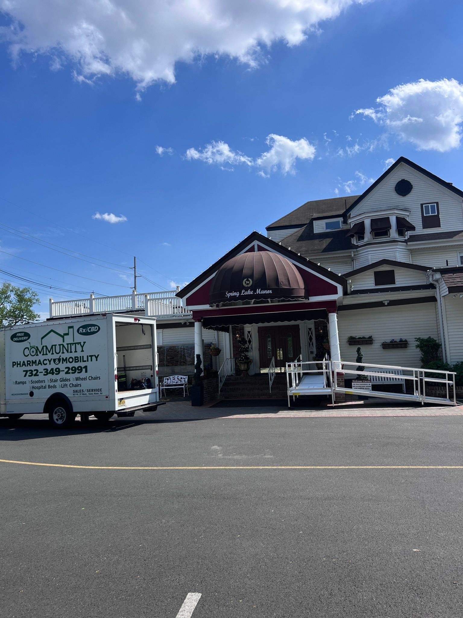 Building entrance with steps and ramp, white exterior, red awning. Service van parked on the side. Blue sky.