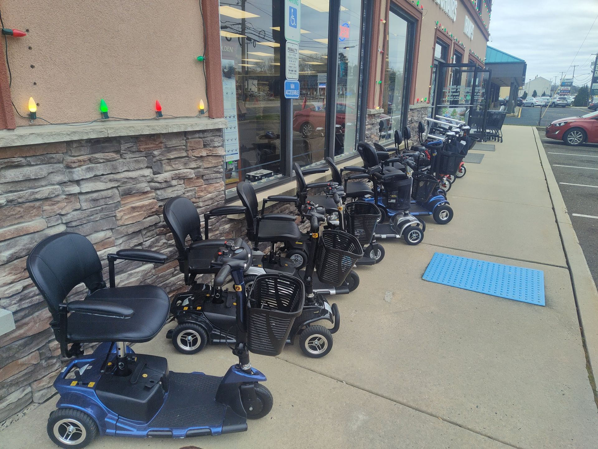 Mobility scooters parked in a row outside a store with a wheelchair-accessible ramp.