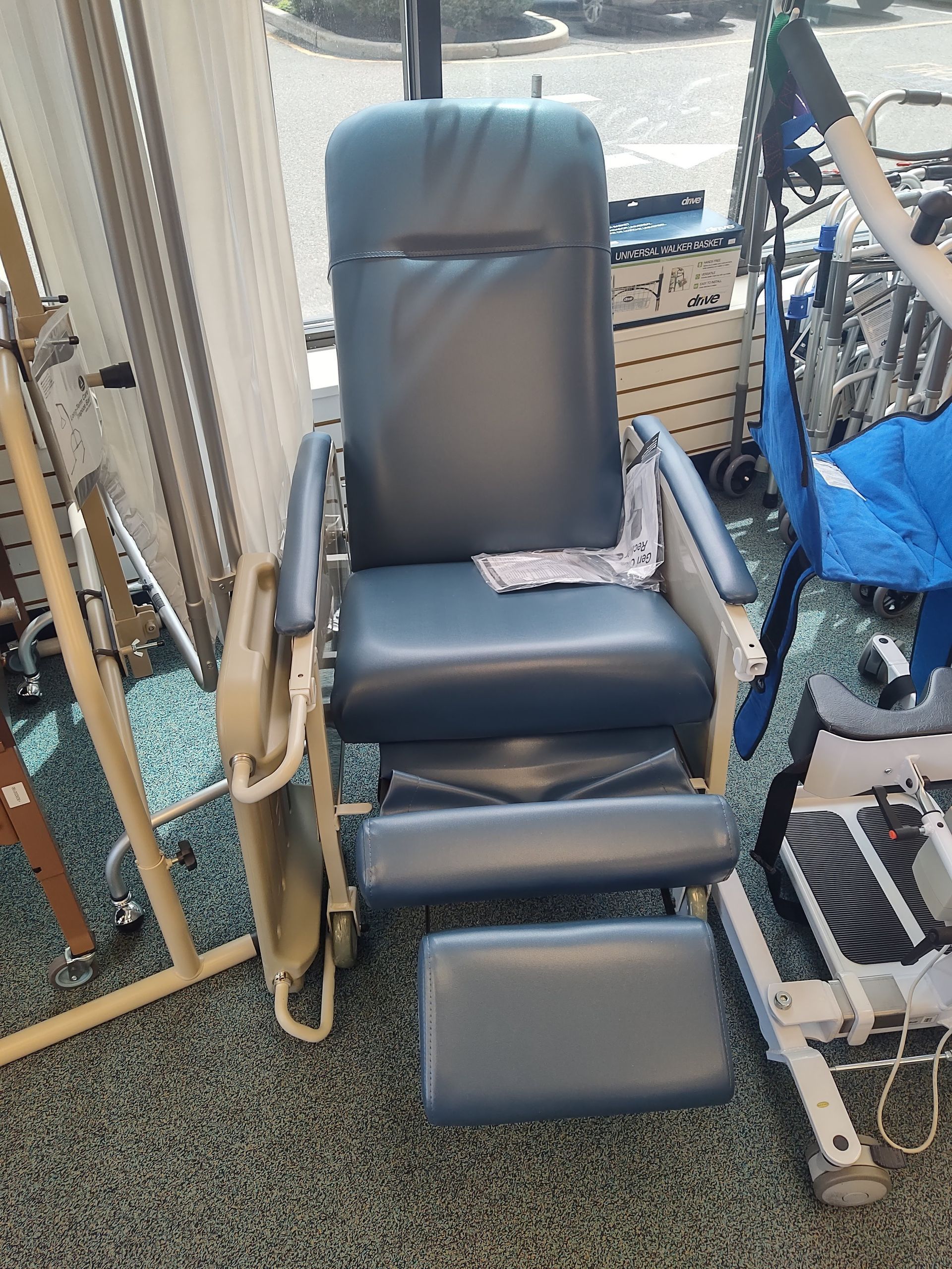 Blue reclining medical chair with leg rest, in a room with other medical equipment.