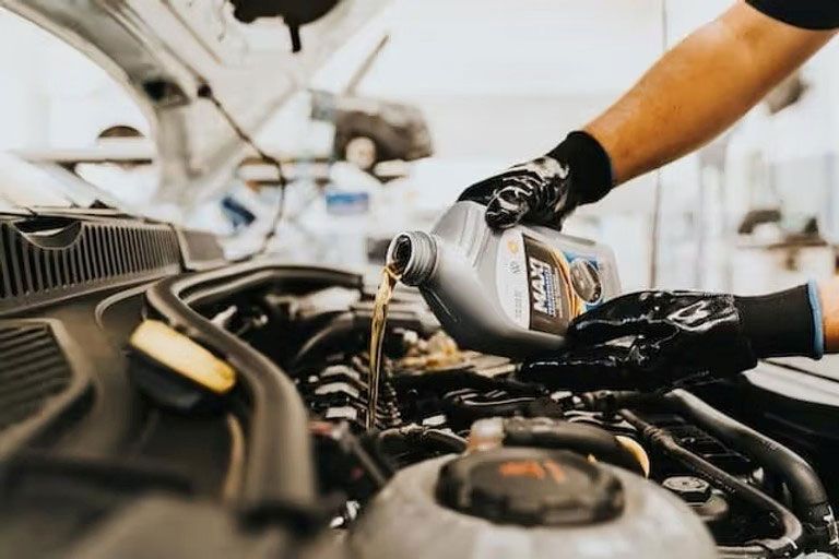Mechanic pouring oil into a car engine in a workshop