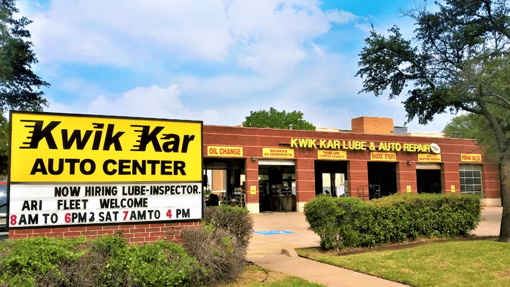 Kwik Kar Auto Center storefront with yellow sign and brick building under a blue sky