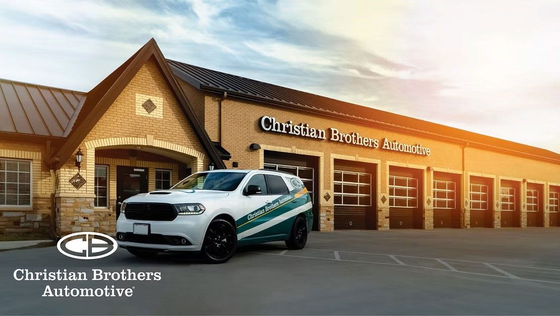 Christian Brothers Automotive storefront with a white and teal service vehicle parked outside at sunset