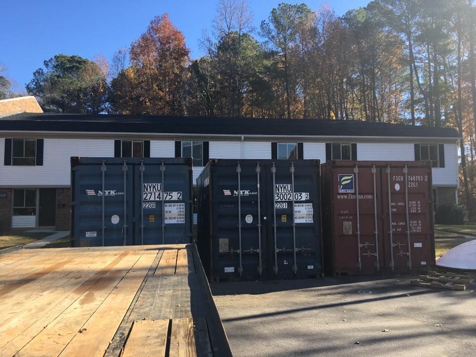 A row of shipping containers are parked in front of a house