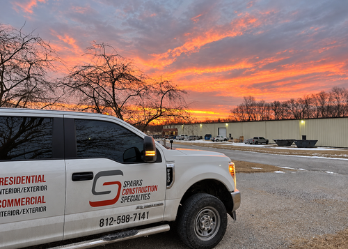 Snowy work truck at sunset with orange sky and commercial service logo on the door