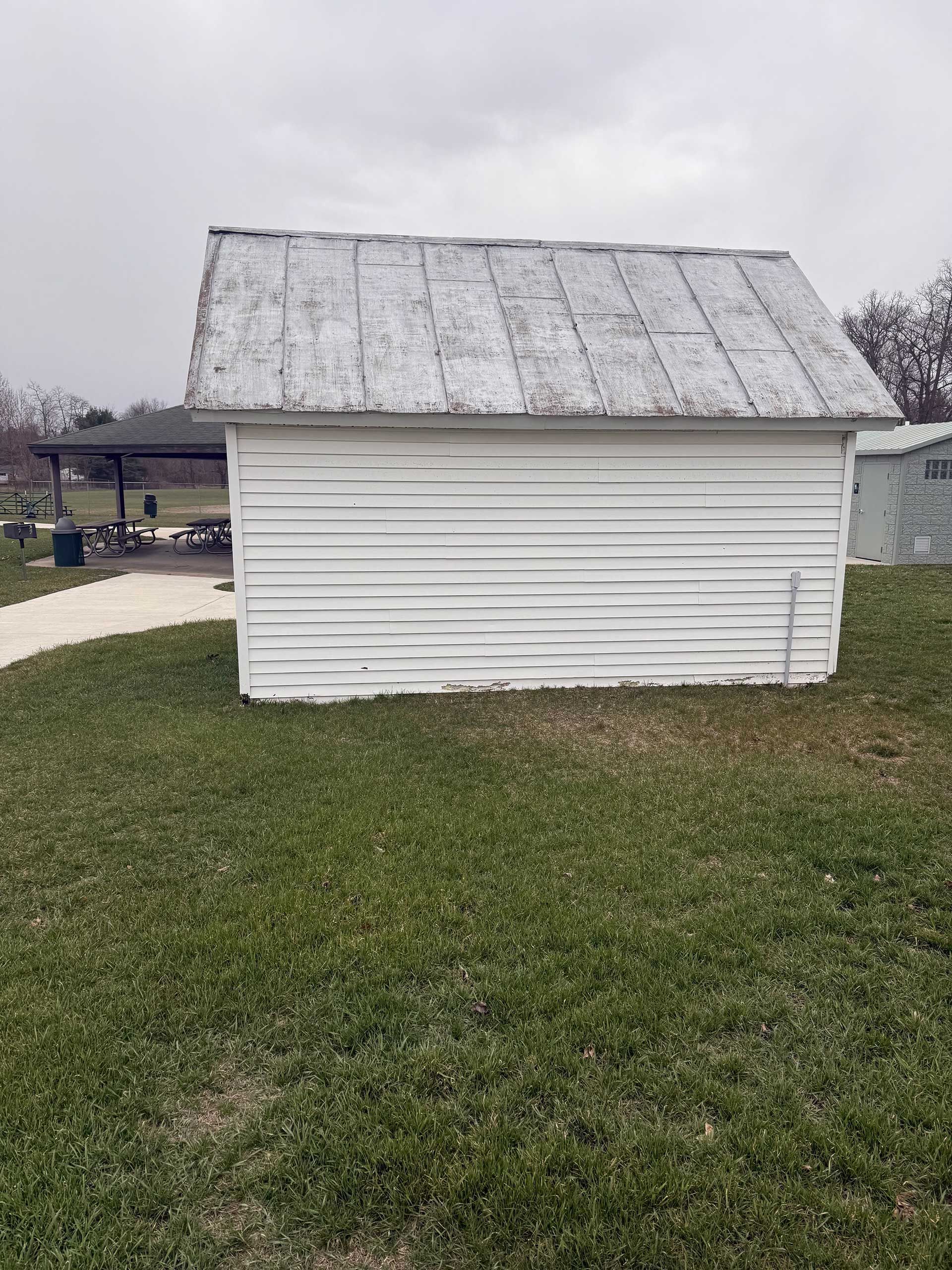 a small white shed in the middle of a grassy field