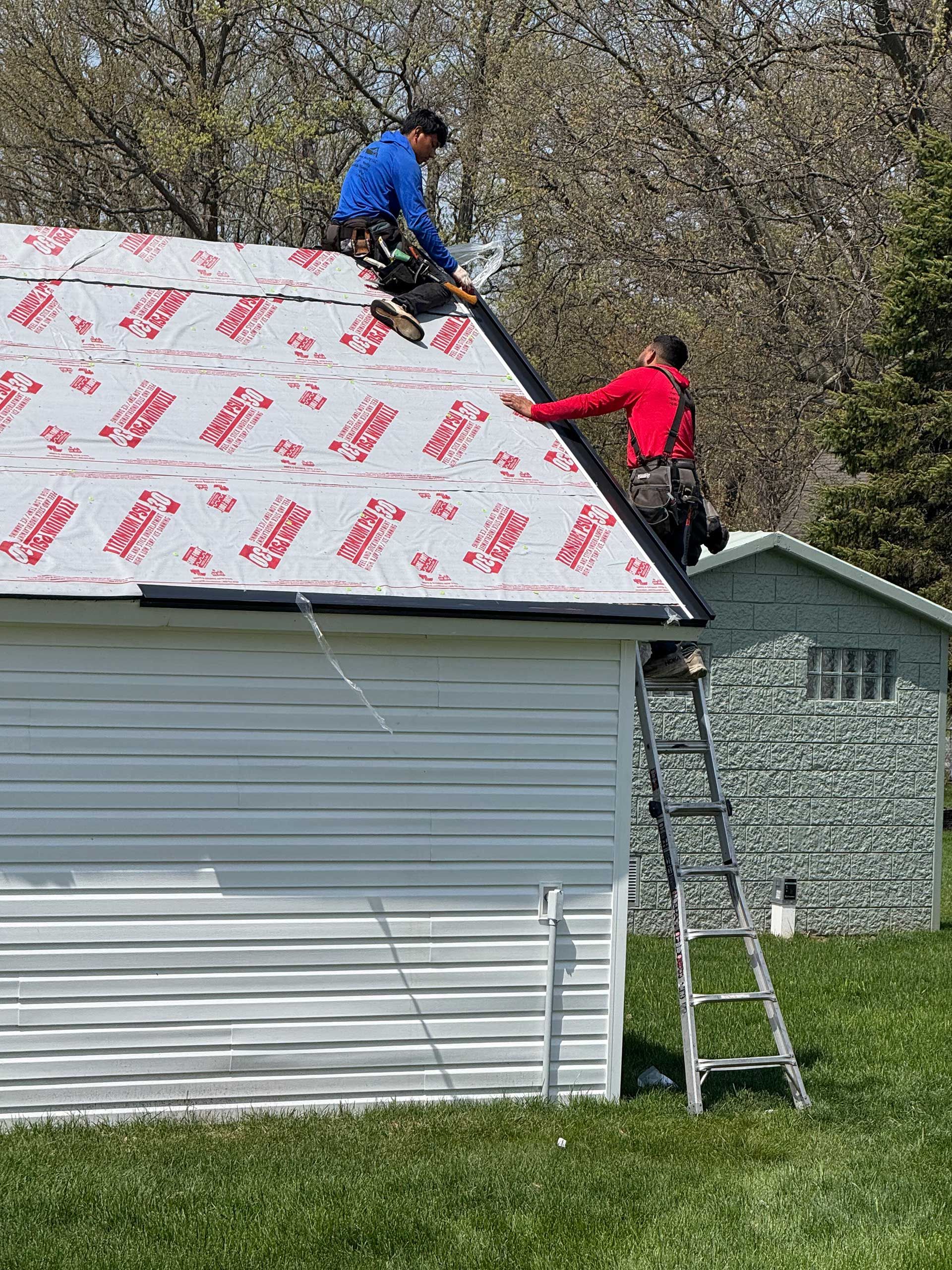 two men are working on the roof of a garage